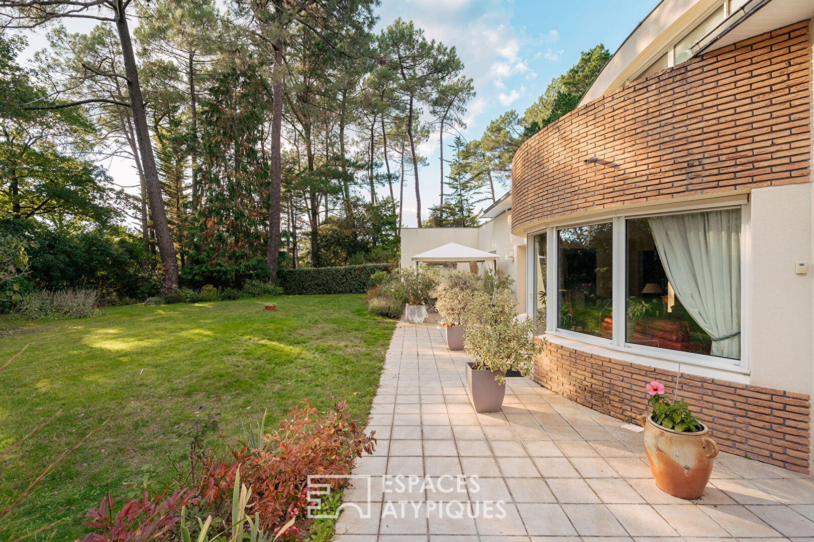 Maison d'Architecte avec jardin paysager dans un environnement boisé.