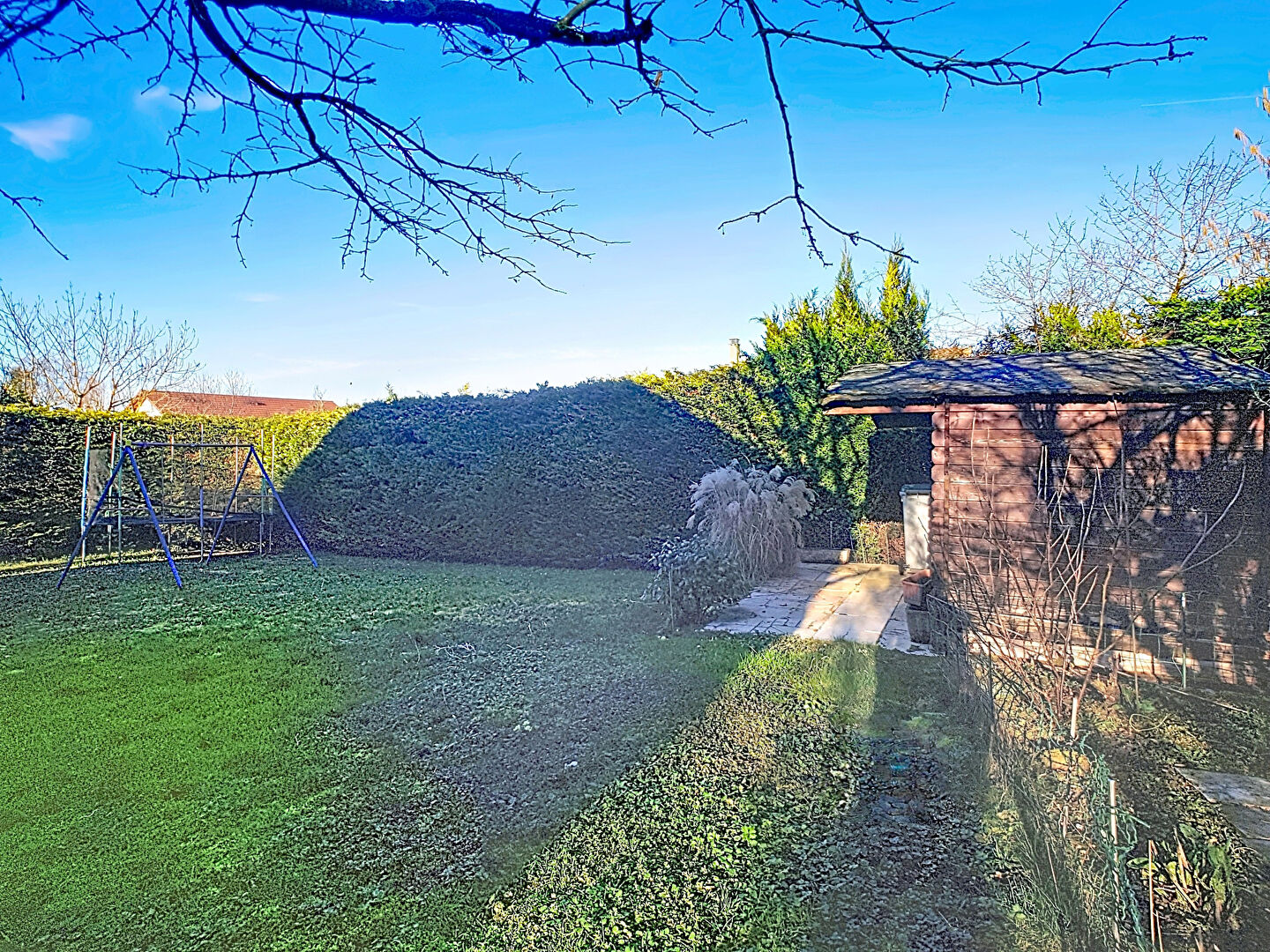 Spacious garden with a shed and swing set in Haute-Savoie, Auvergne-Rhône-Alpes, featuring lush greenery.