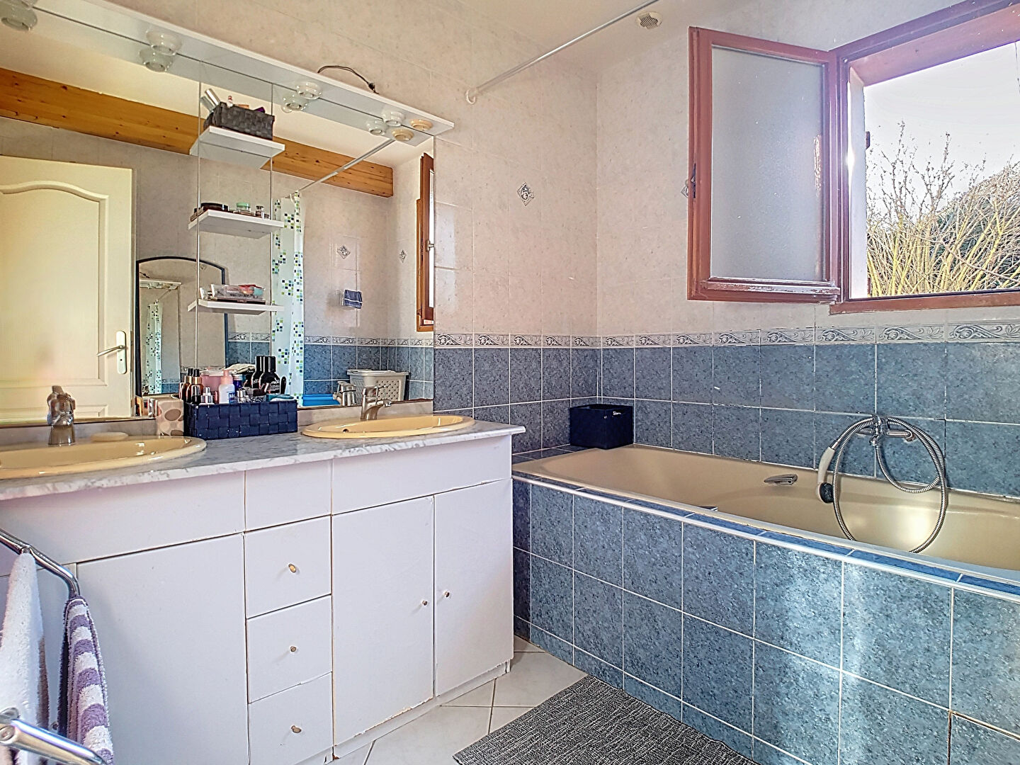Spacious property in Haute-Savoie featuring a well-lit bathroom with dual sinks and a bathtub.
