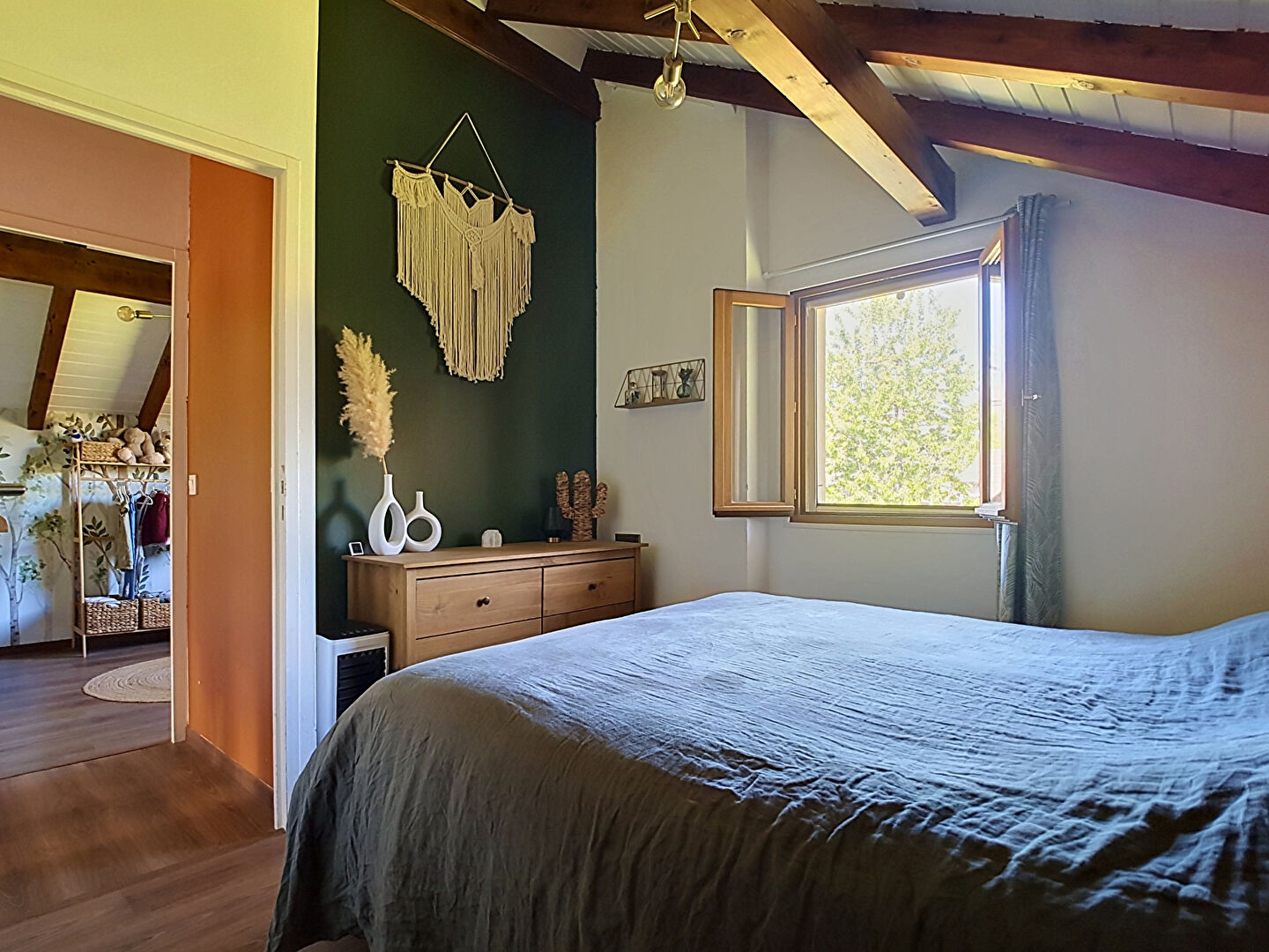 Spacious bedroom with wooden beams, window view, and stylish decor in Haute-Savoie, Auvergne-Rhône-Alpes.