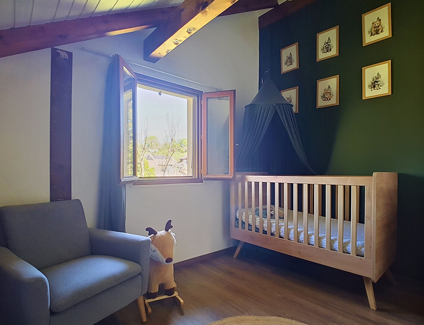 Three-bedroom property in Haute-Savoie featuring a nursery with a wooden crib and scenic window view.