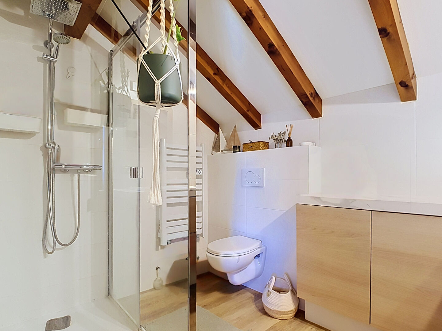 Modern property in Haute-Savoie featuring a stylish bathroom with wooden beams, shower, and contemporary fixtures.