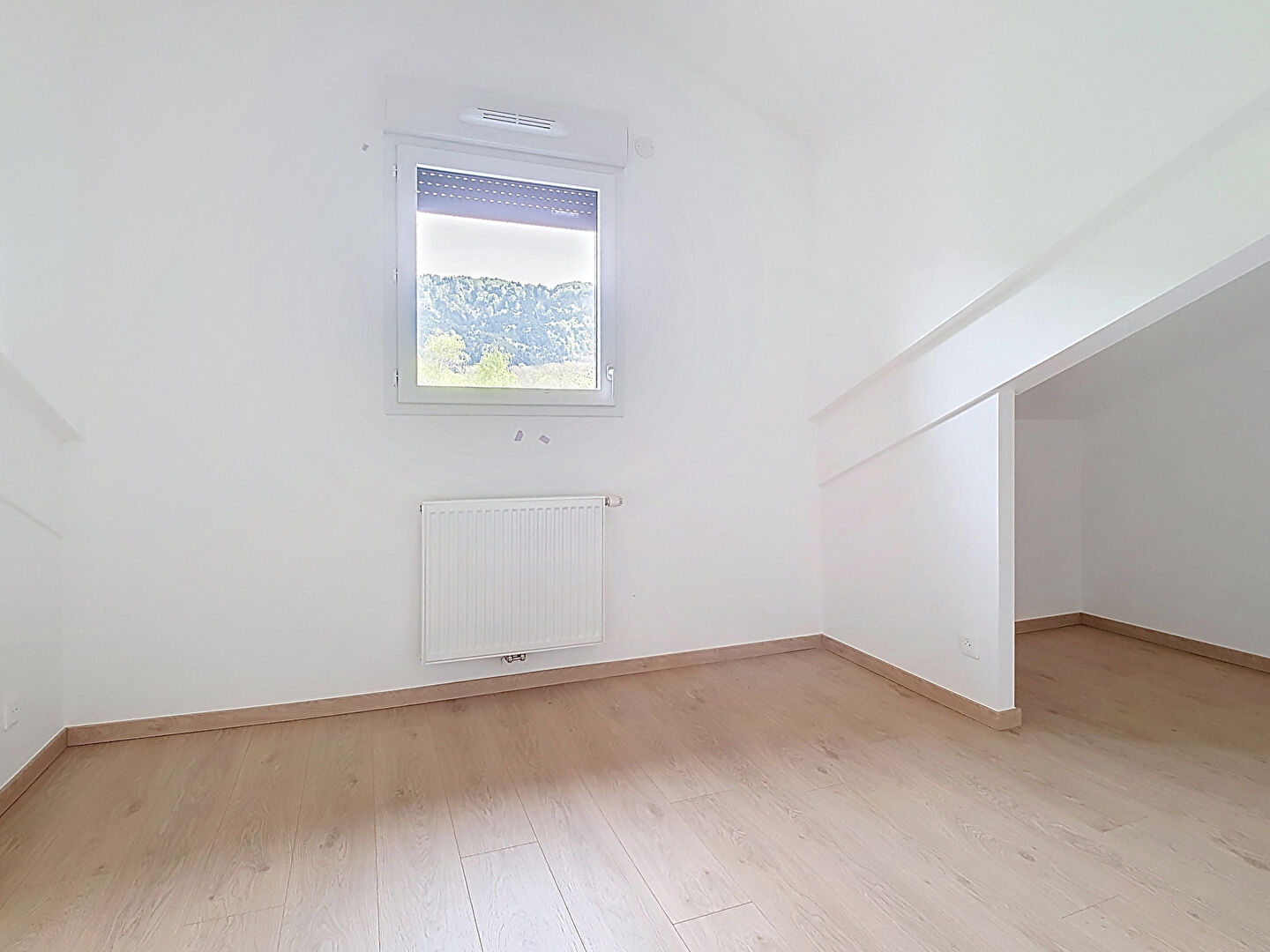 Bright interior of property in Haute-Savoie, featuring wooden flooring and a window with mountain views.