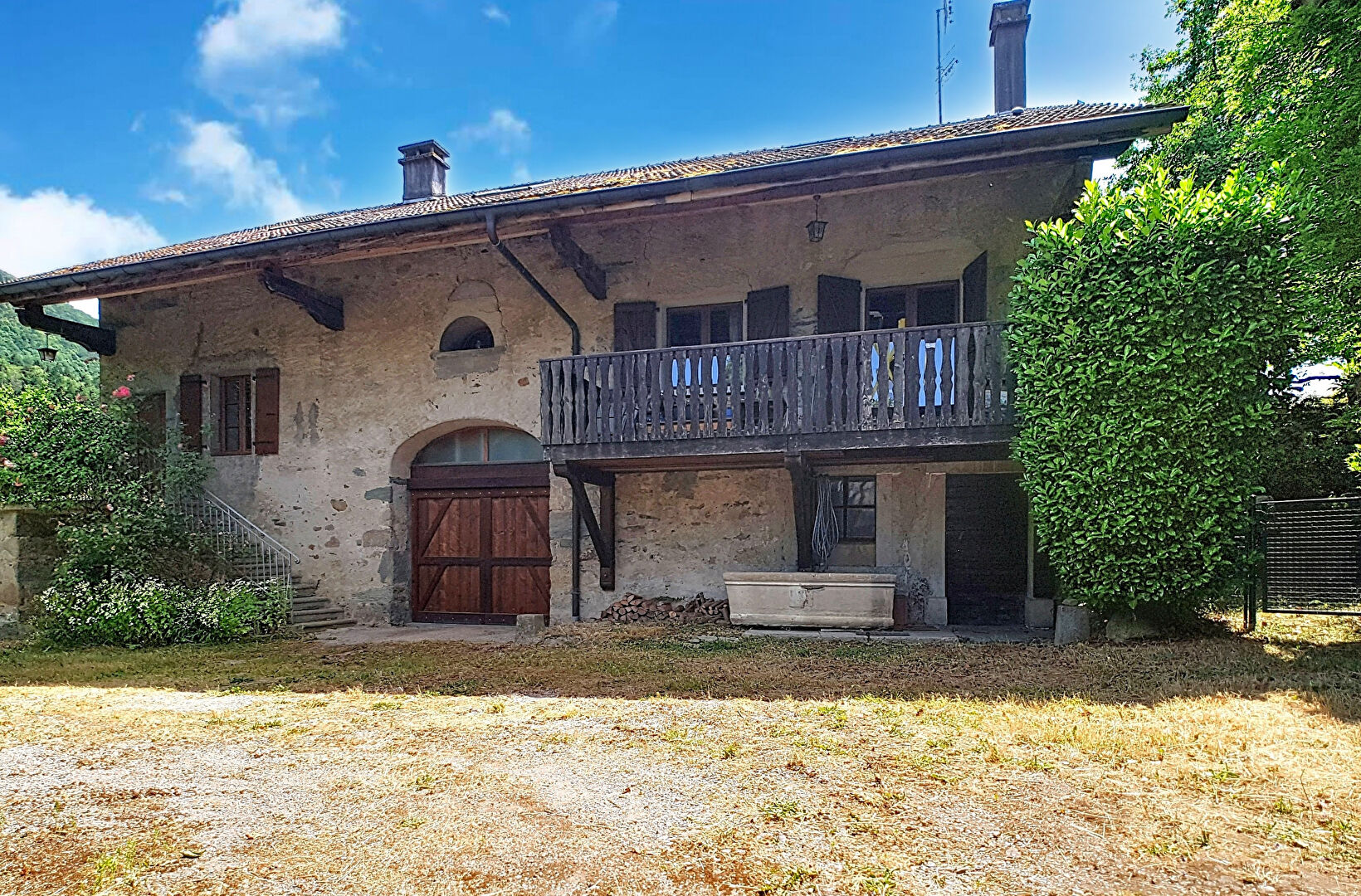 Three-bedroom property in Haute-Savoie featuring a wooden balcony, stone exterior, and garden space.