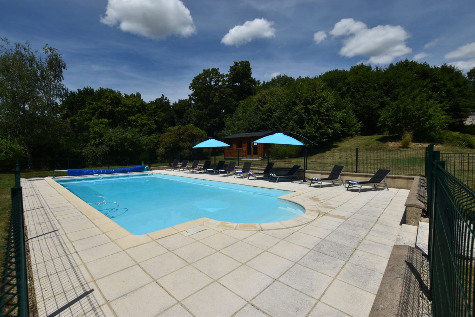 Swimming pool surrounded by sun loungers and umbrellas in Haute-Vienne, Nouvelle-Aquitaine, featuring extensive garden space.