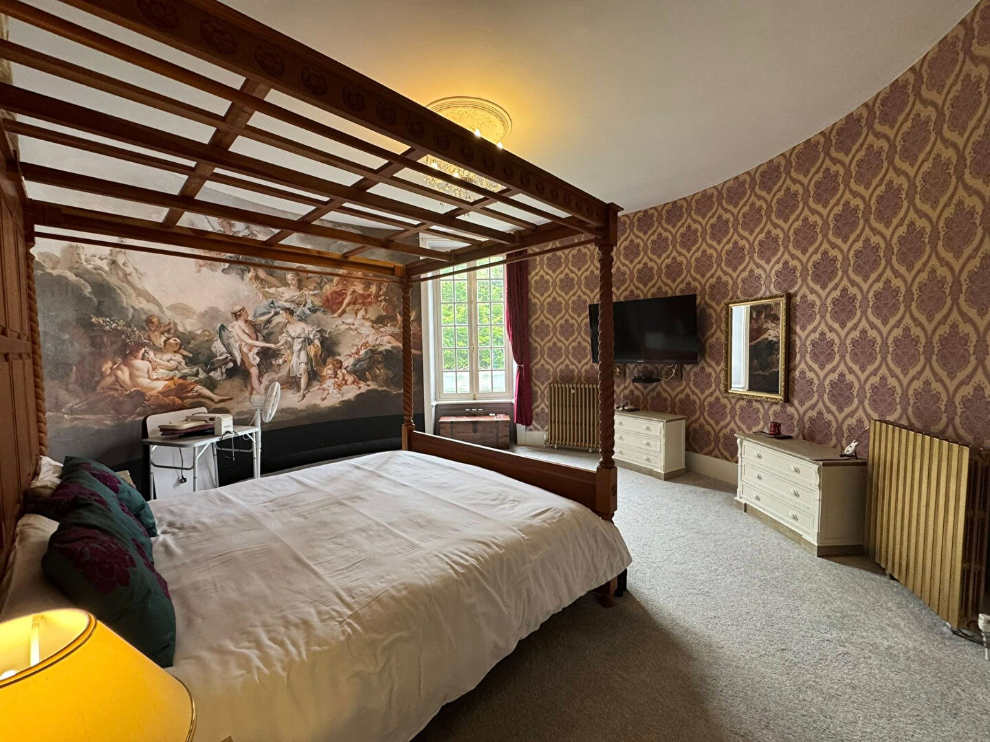 Spacious property in Haute-Vienne featuring a four-poster bed, ornate wallpaper, and large windows.