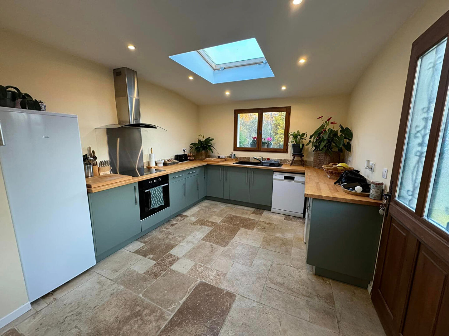 Modern kitchen with wood countertops and skylight in a property located in Haute-Vienne, Nouvelle-Aquitaine.