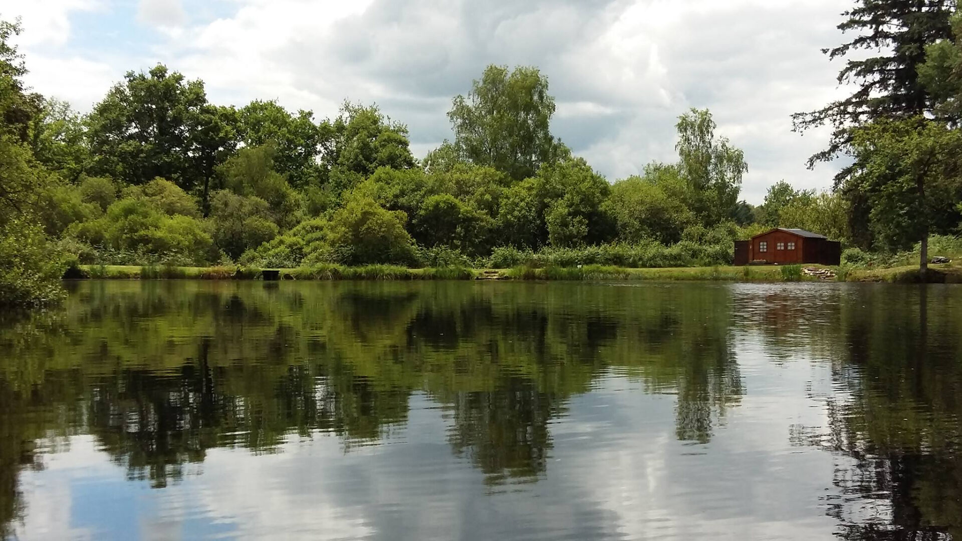 Tranquil scene of a property by a lake in Haute-Vienne, Nouvelle-Aquitaine, surrounded by lush greenery.