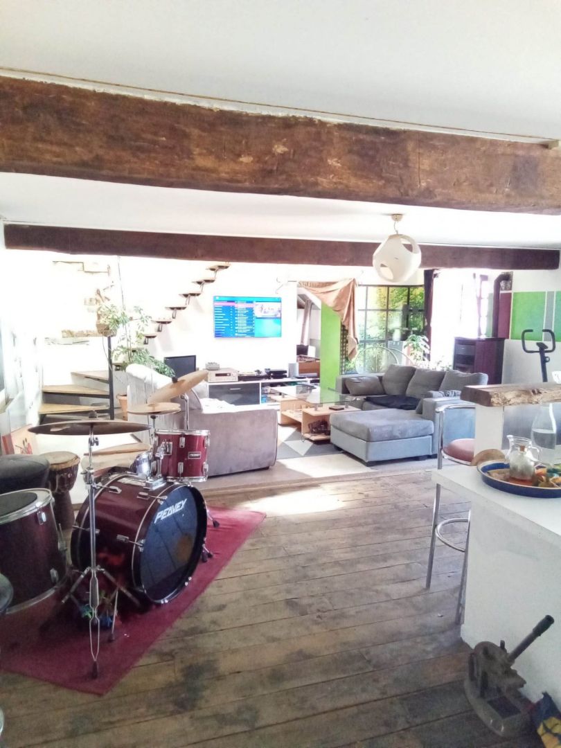 Spacious property in Creuse featuring a modern living area with wooden beams and musical instruments.