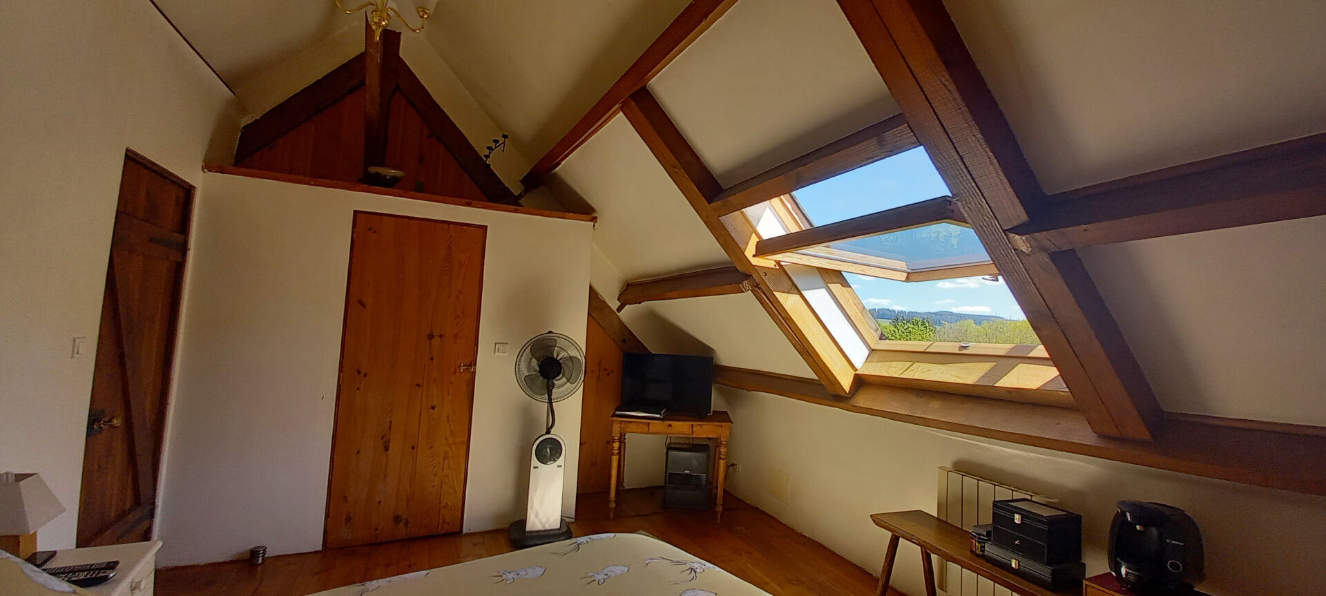 Bright bedroom with wooden beams, fan, and scenic views in a property located in Haute-Vienne, Nouvelle-Aquitaine.
