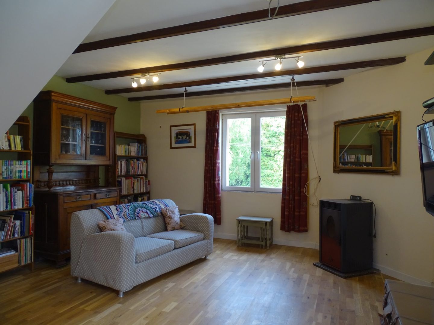 Three-bedroom property in Côtes-d'Armor featuring wooden beams, a cosy lounge area, and large windows for natural light.