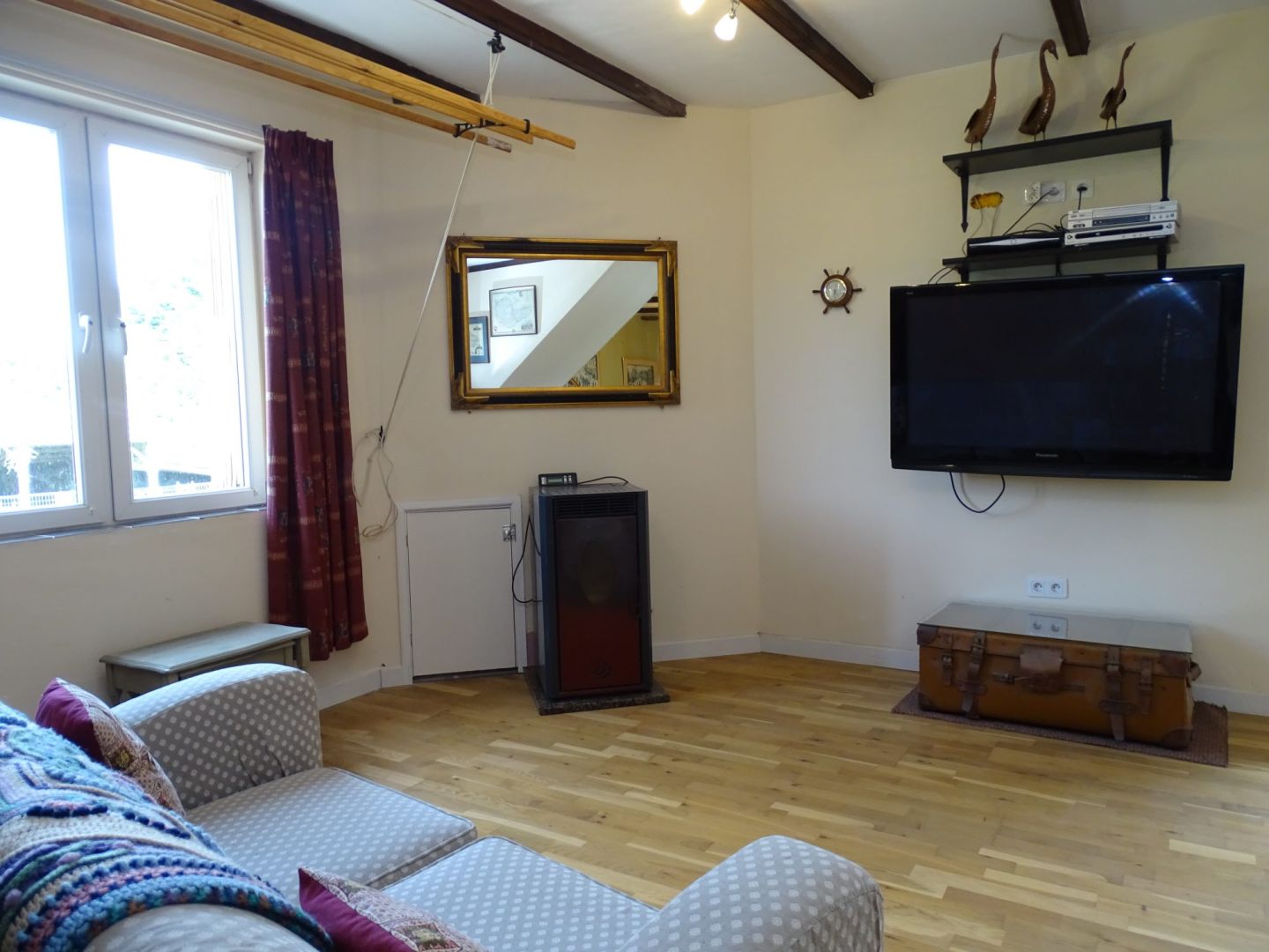 Spacious living area with wooden beams, television, and natural light in a property located in Côtes-d'Armor, Brittany.