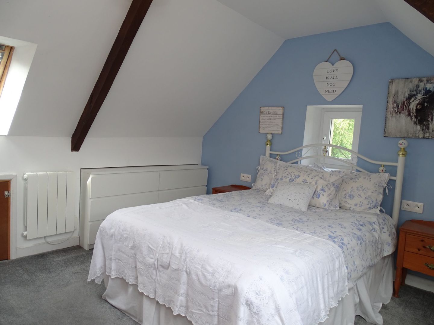Spacious bedroom with sloped ceiling and floral decor in a property located in Côtes-d'Armor, Brittany.