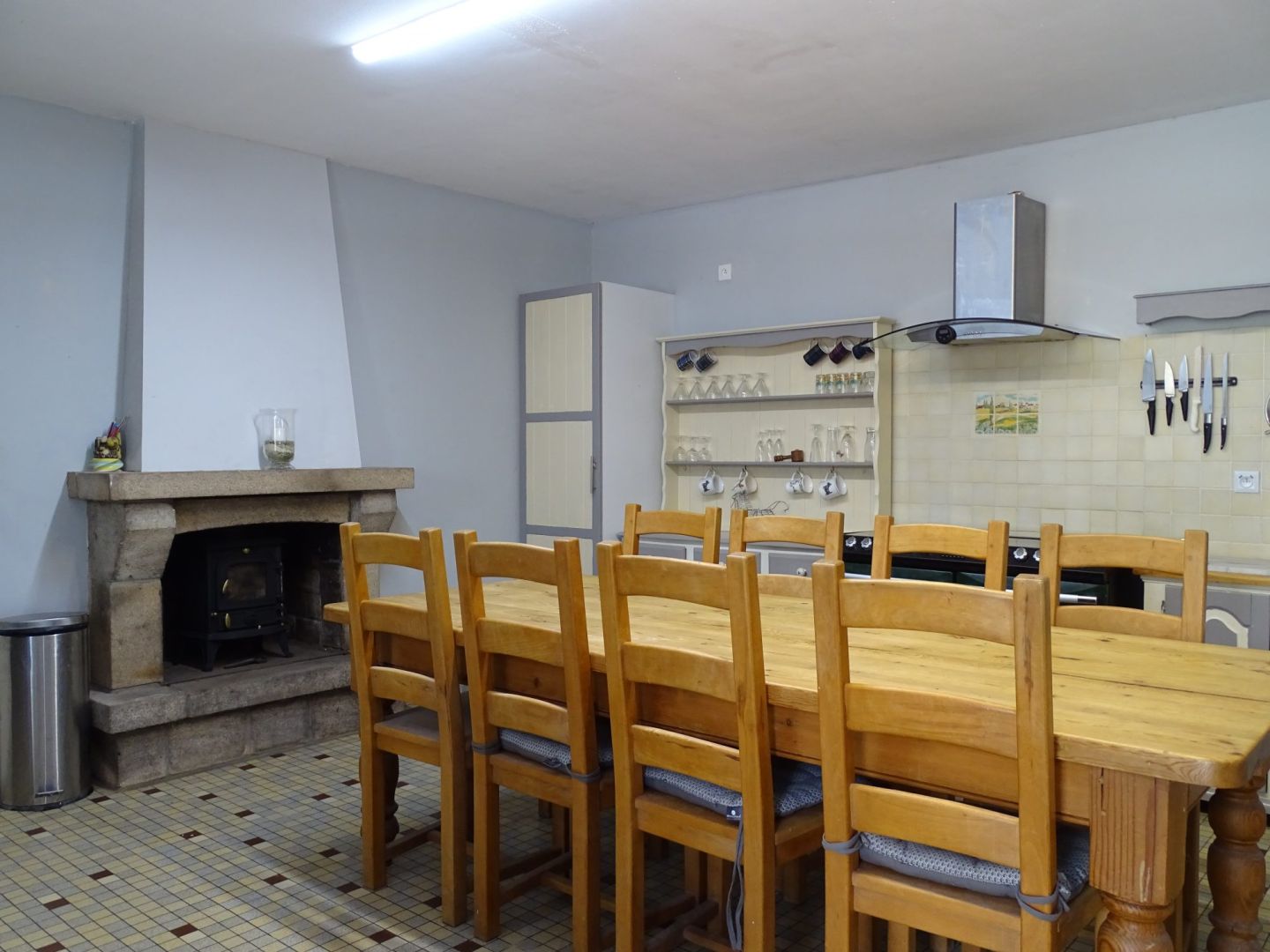 Spacious kitchen with wooden dining table and fireplace in Côtes-d'Armor, Brittany, featuring three bedrooms.