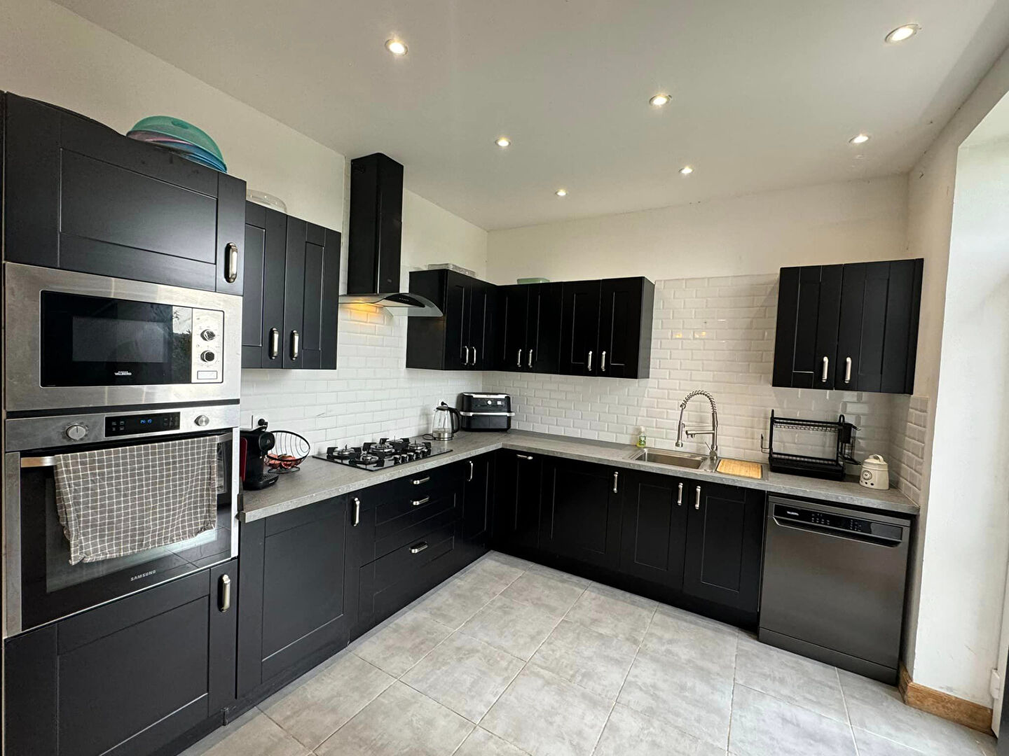 Modern kitchen with sleek black cabinetry and grey tiles in a property located in Haute-Vienne, Nouvelle-Aquitaine.