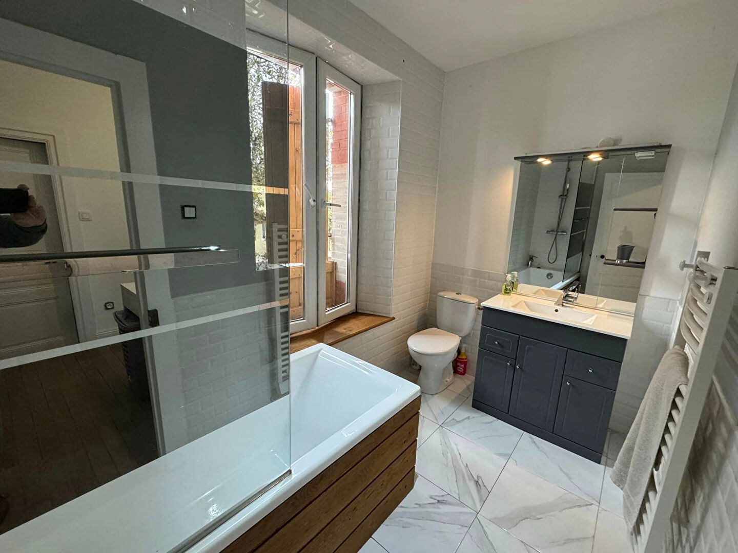 Modern property in Haute-Vienne featuring a stylish bathroom with a bath, shower, and natural light from large windows.