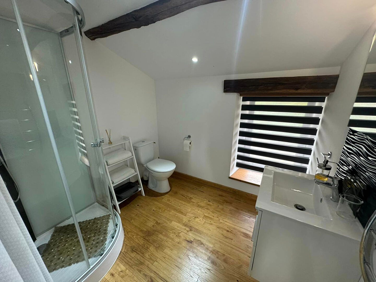 Spacious property in Haute-Vienne featuring modern bathroom with shower, wooden flooring, and sleek design elements.