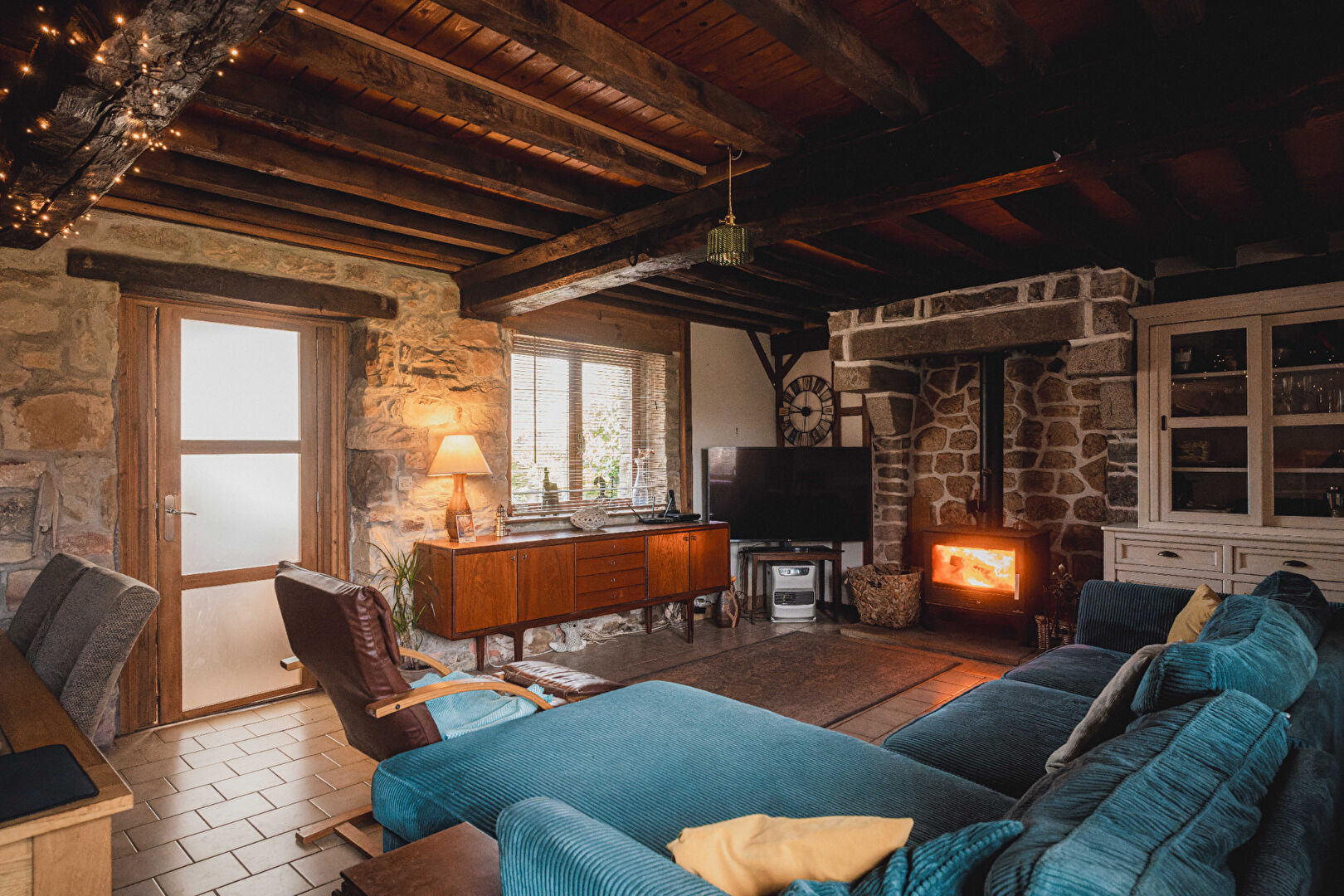 Cosy property in Orne, Normandy, featuring a stone fireplace, wooden beams, and spacious living area with comfortable seating