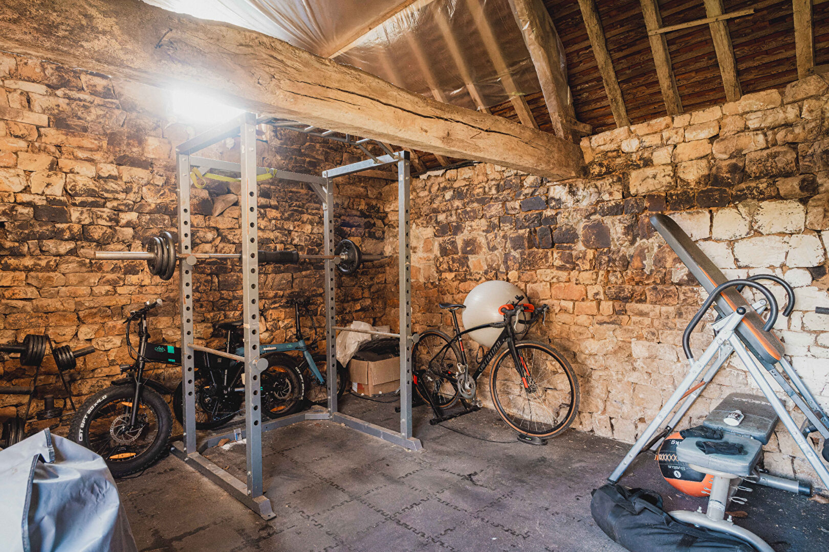 Spacious property in Orne, Normandy, featuring a gym area with equipment and exposed stone walls.