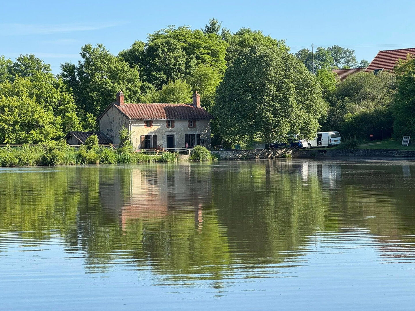 Two-bedroom property in Haute-Vienne, Nouvelle-Aquitaine, beside a tranquil lake with lush greenery.