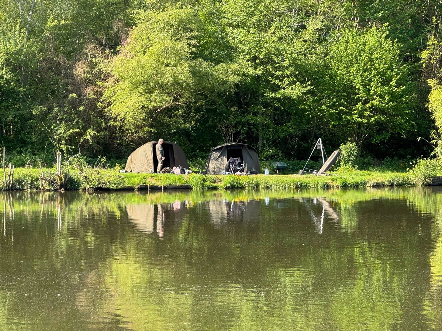 Two camping tents by a tranquil lake surrounded by lush greenery in Haute-Vienne, Nouvelle-Aquitaine.