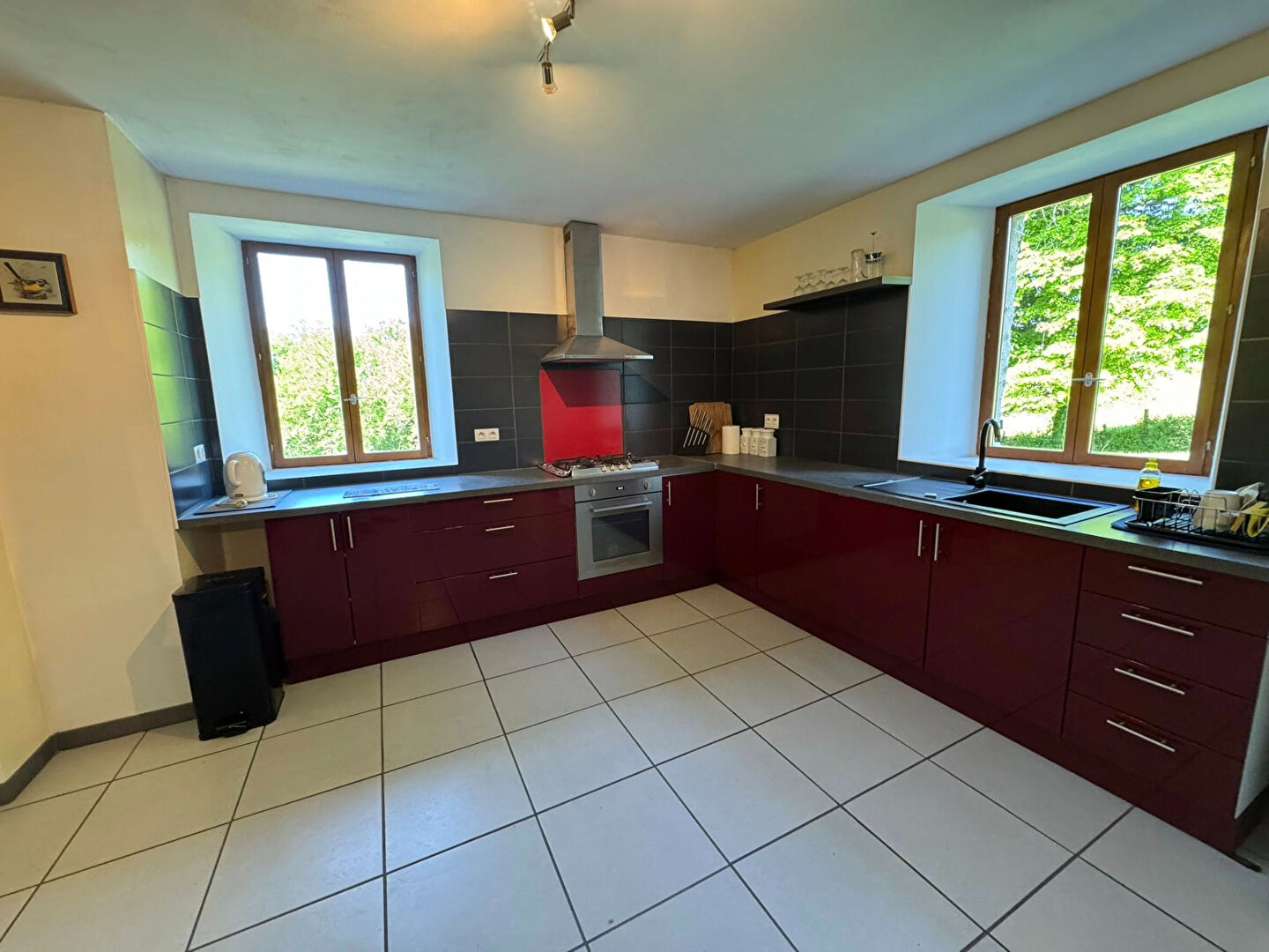 Modern kitchen featuring red cabinetry and large windows in Haute-Vienne, Nouvelle-Aquitaine, 87800, France.