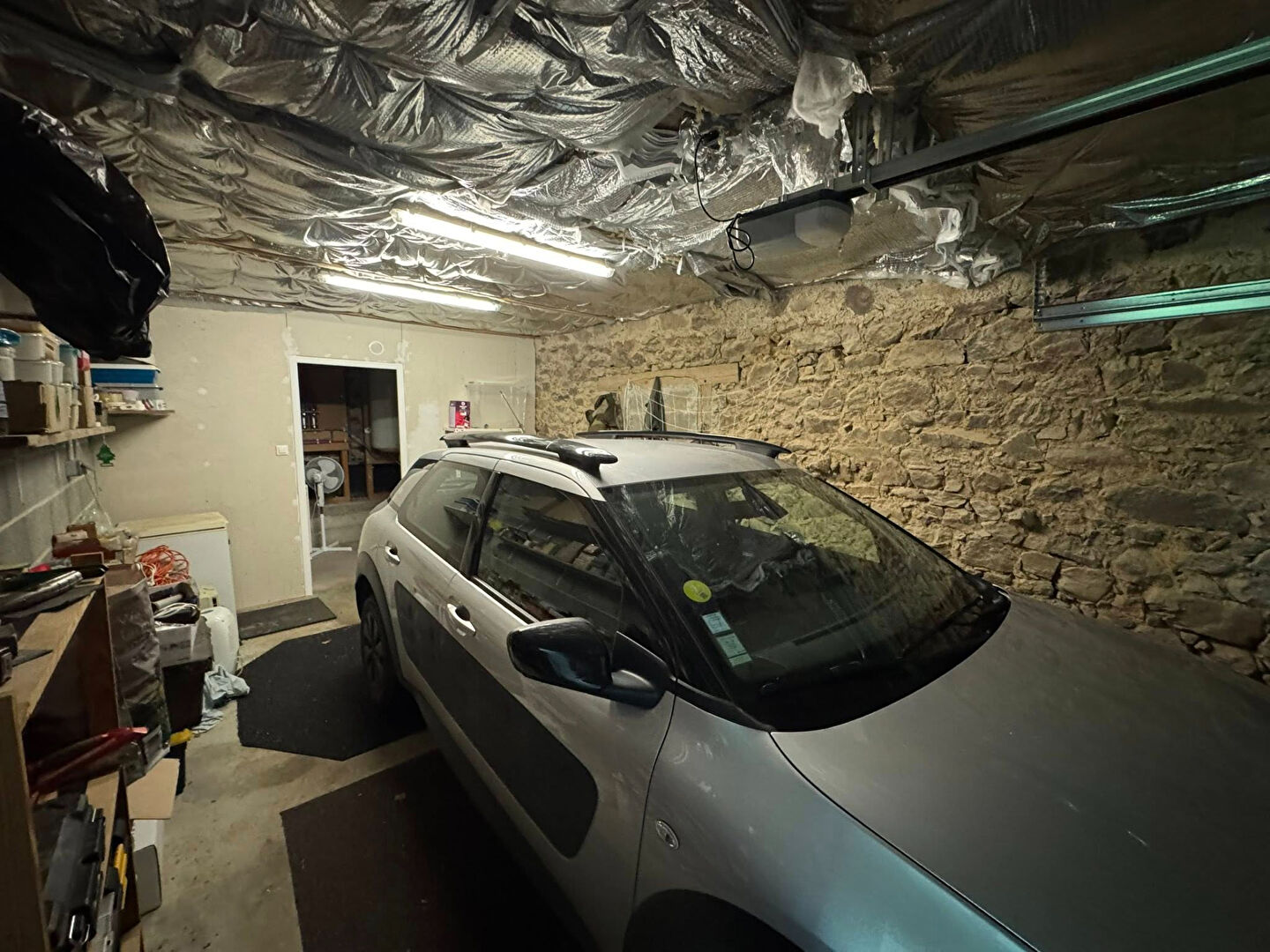 Two-bedroom property in Haute-Vienne featuring a garage with stone walls and modern lighting.