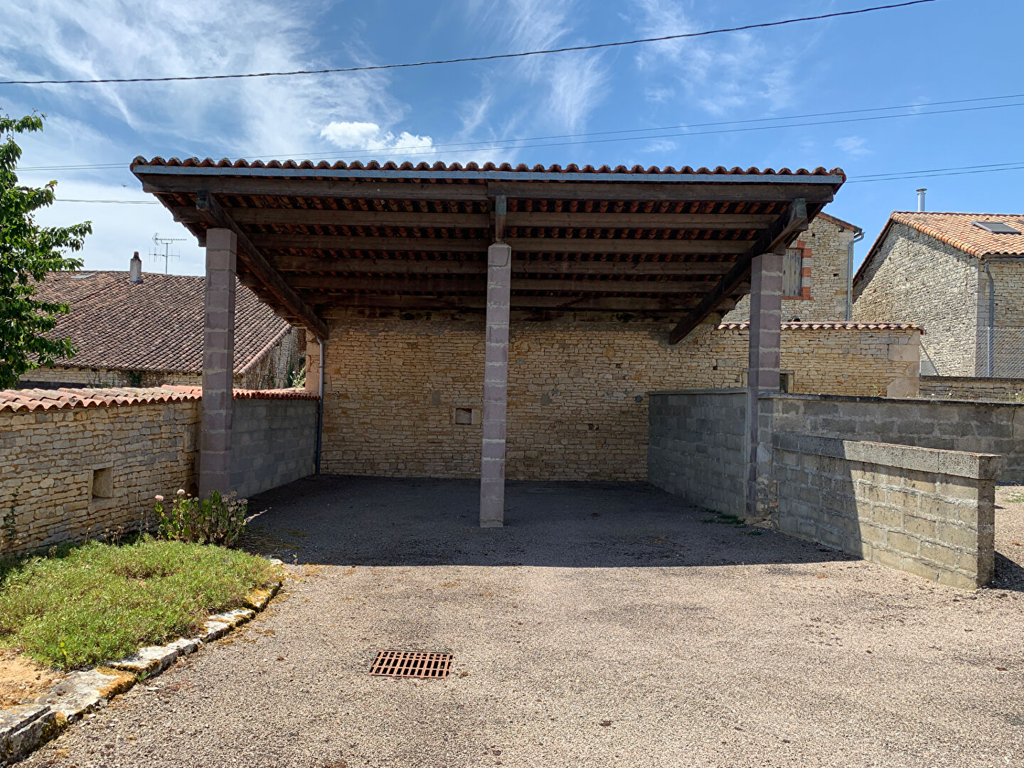 Covered parking area with stone walls in Charente, Nouvelle-Aquitaine, ideal for a property with two bedrooms.