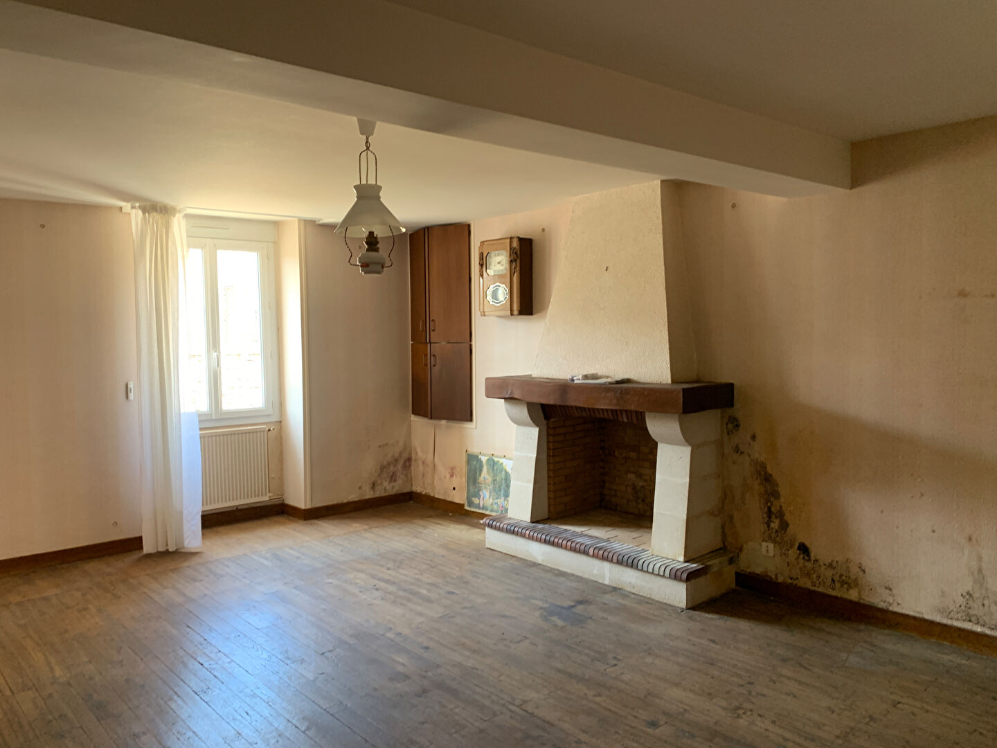 Spacious interior of a property in Charente, Nouvelle-Aquitaine, featuring a fireplace and wooden flooring.