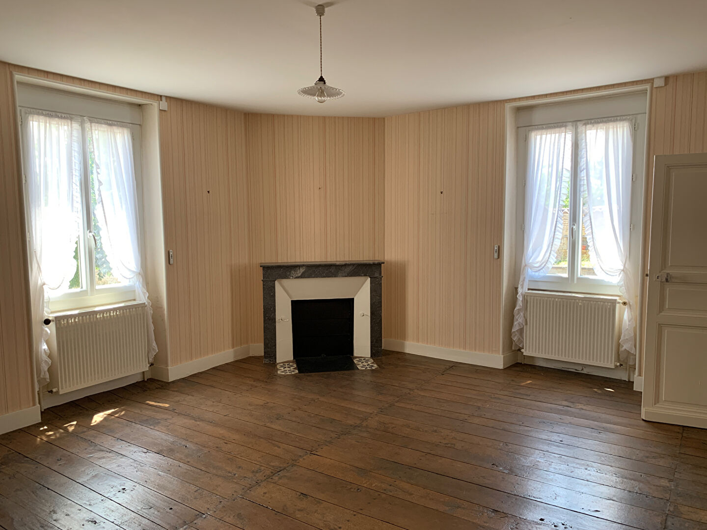 Bright interior of a property in Charente, Nouvelle-Aquitaine, featuring wooden floors and large windows.