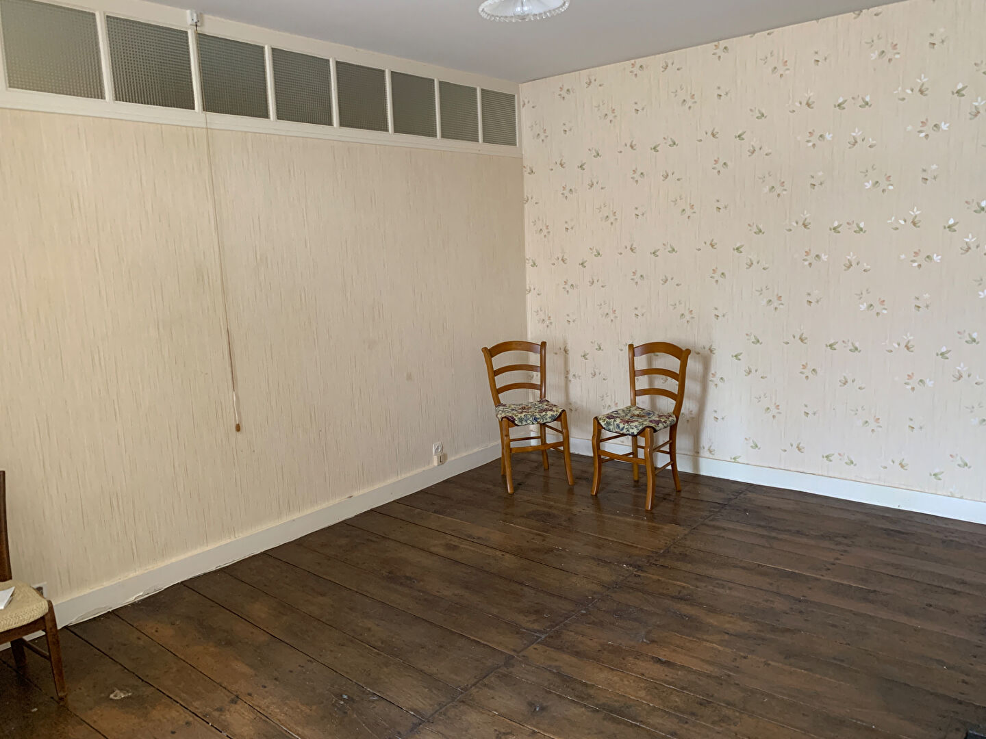 Spacious room in a property located in Charente, Nouvelle-Aquitaine, featuring wooden flooring and floral wallpaper.