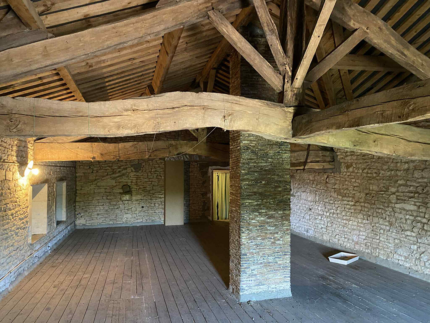 Spacious property in Charente, Nouvelle-Aquitaine, featuring exposed wooden beams and stone walls, ideal for renovation.