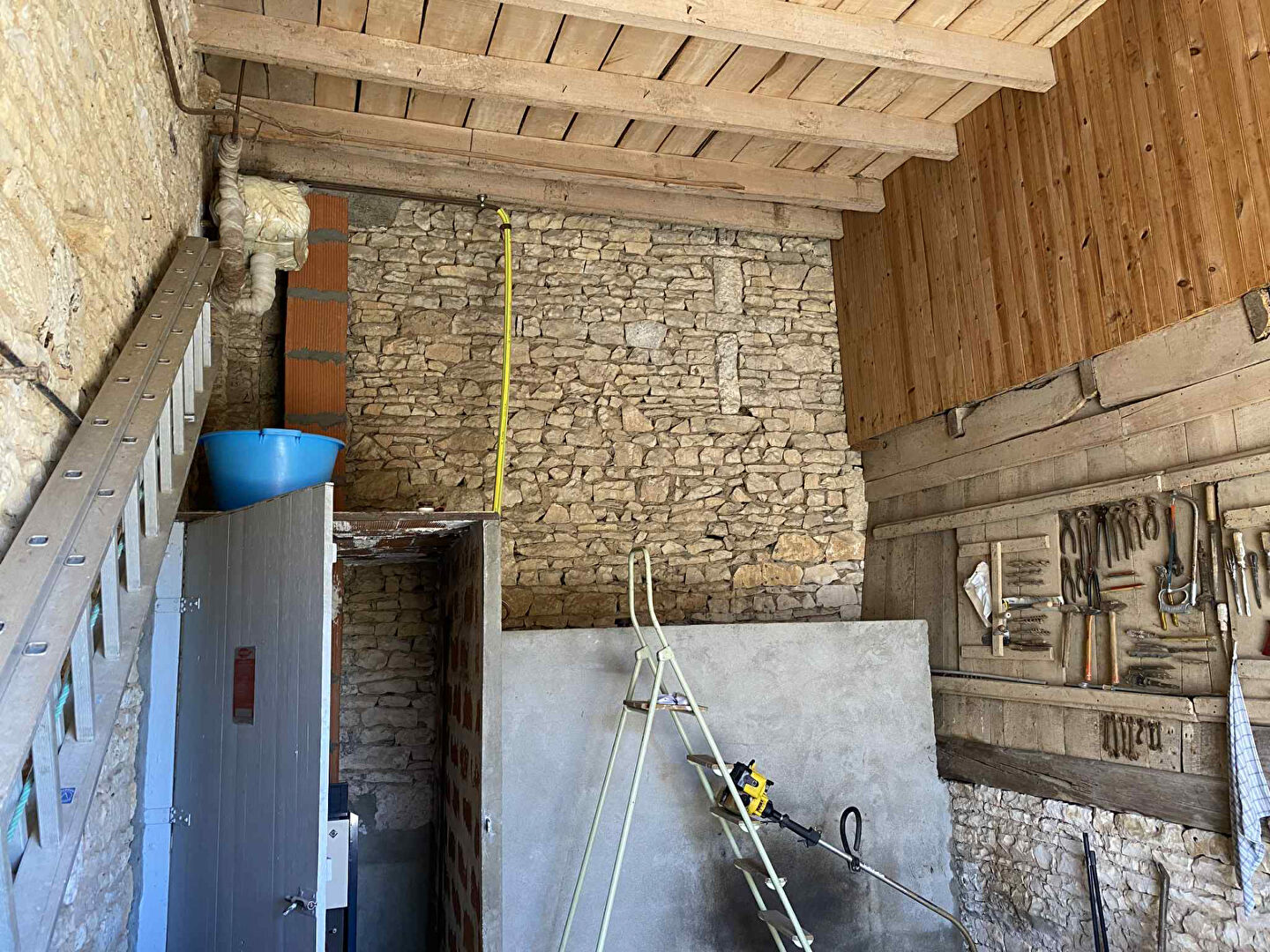 Interior view of a property in Charente, Nouvelle-Aquitaine, featuring exposed stone walls and wooden beams.