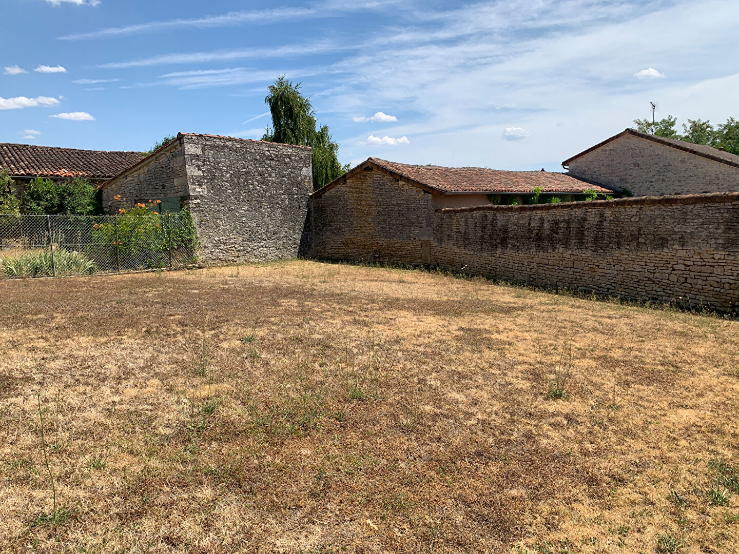 Open land adjacent to residential buildings in Charente, Nouvelle-Aquitaine, ideal for development or garden use.