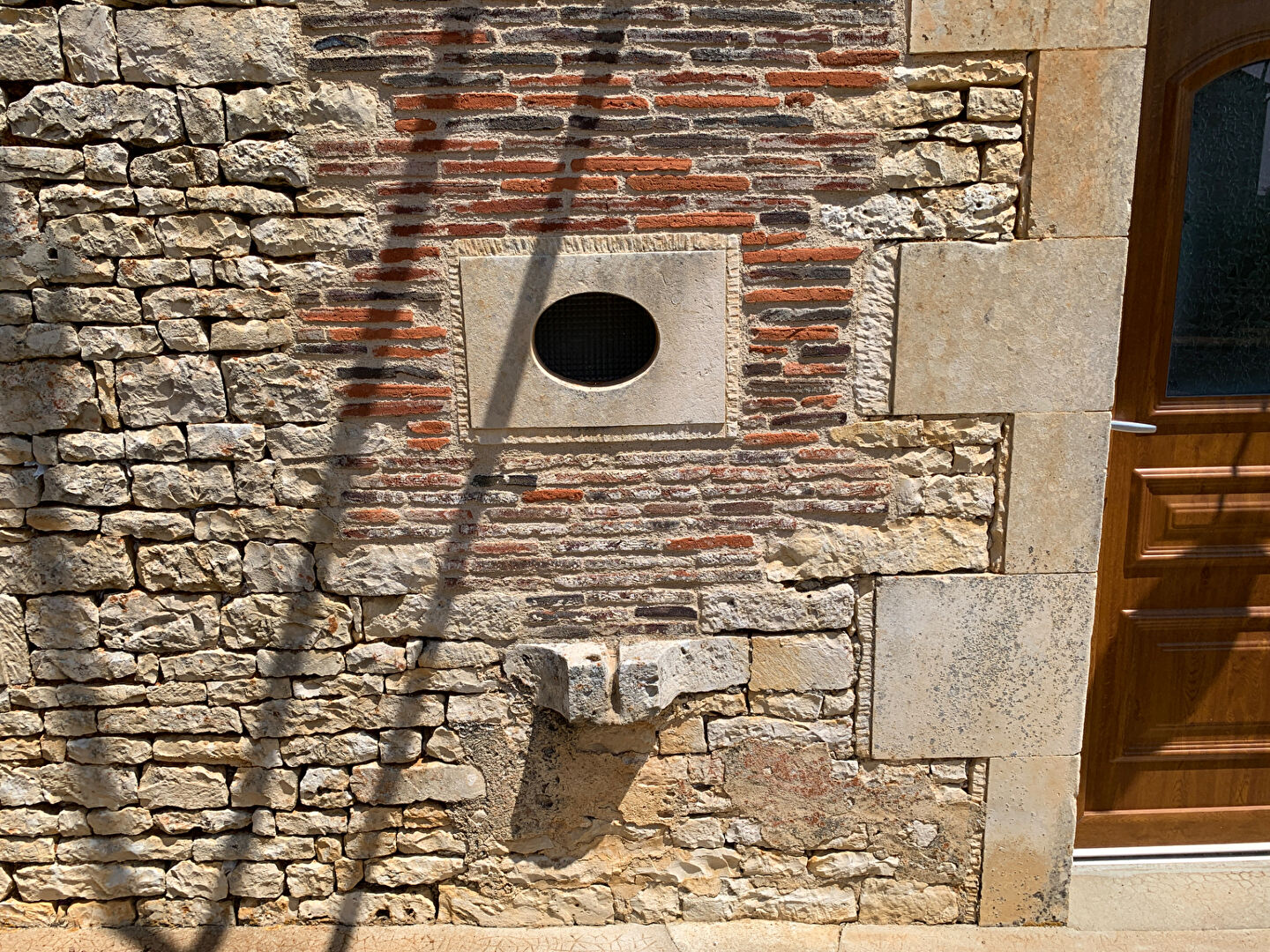 Stone wall detail with a circular window and decorative feature at a property in Charente, Nouvelle-Aquitaine.
