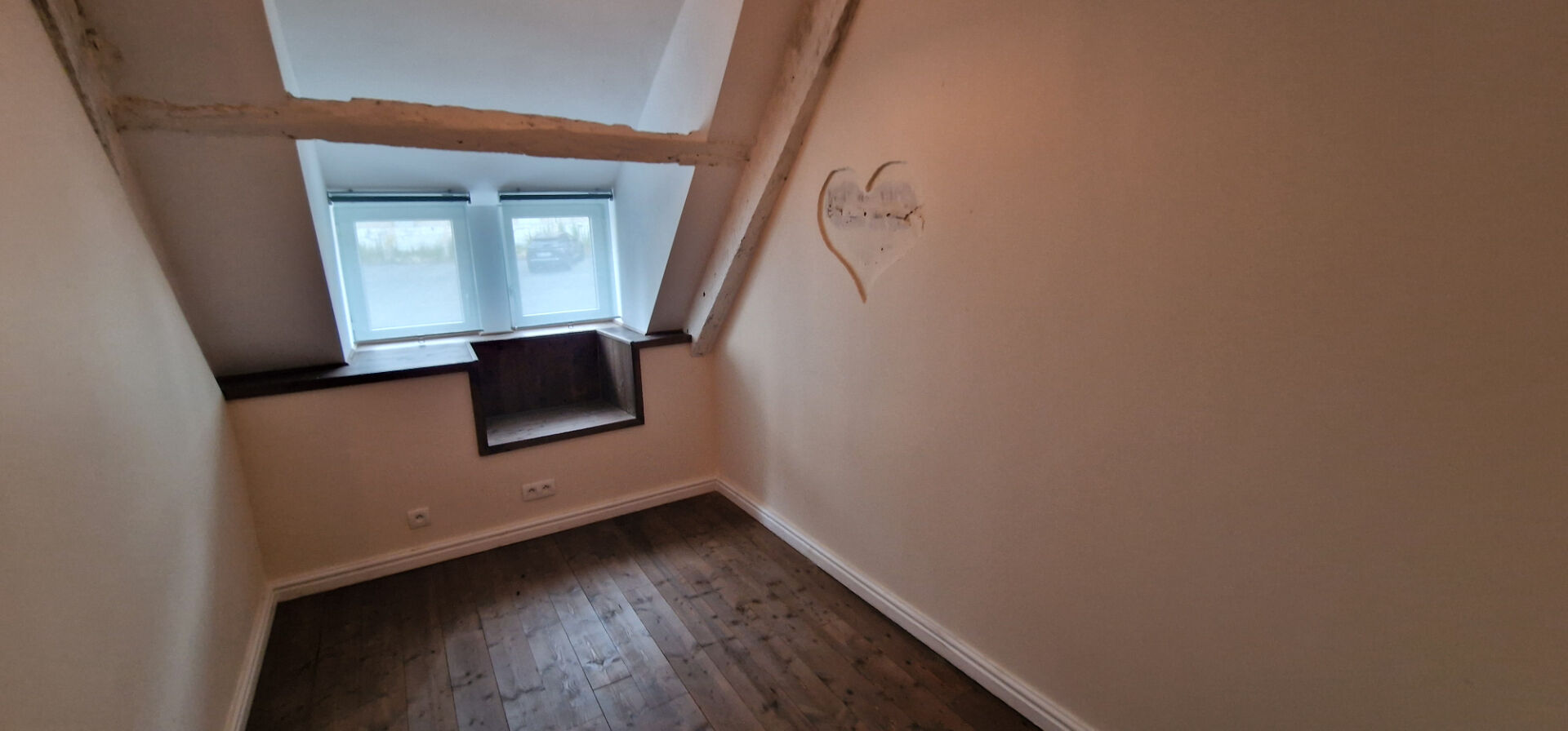 Spacious property in Morbihan, Brittany, featuring a bright, airy room with wooden flooring and dual windows.
