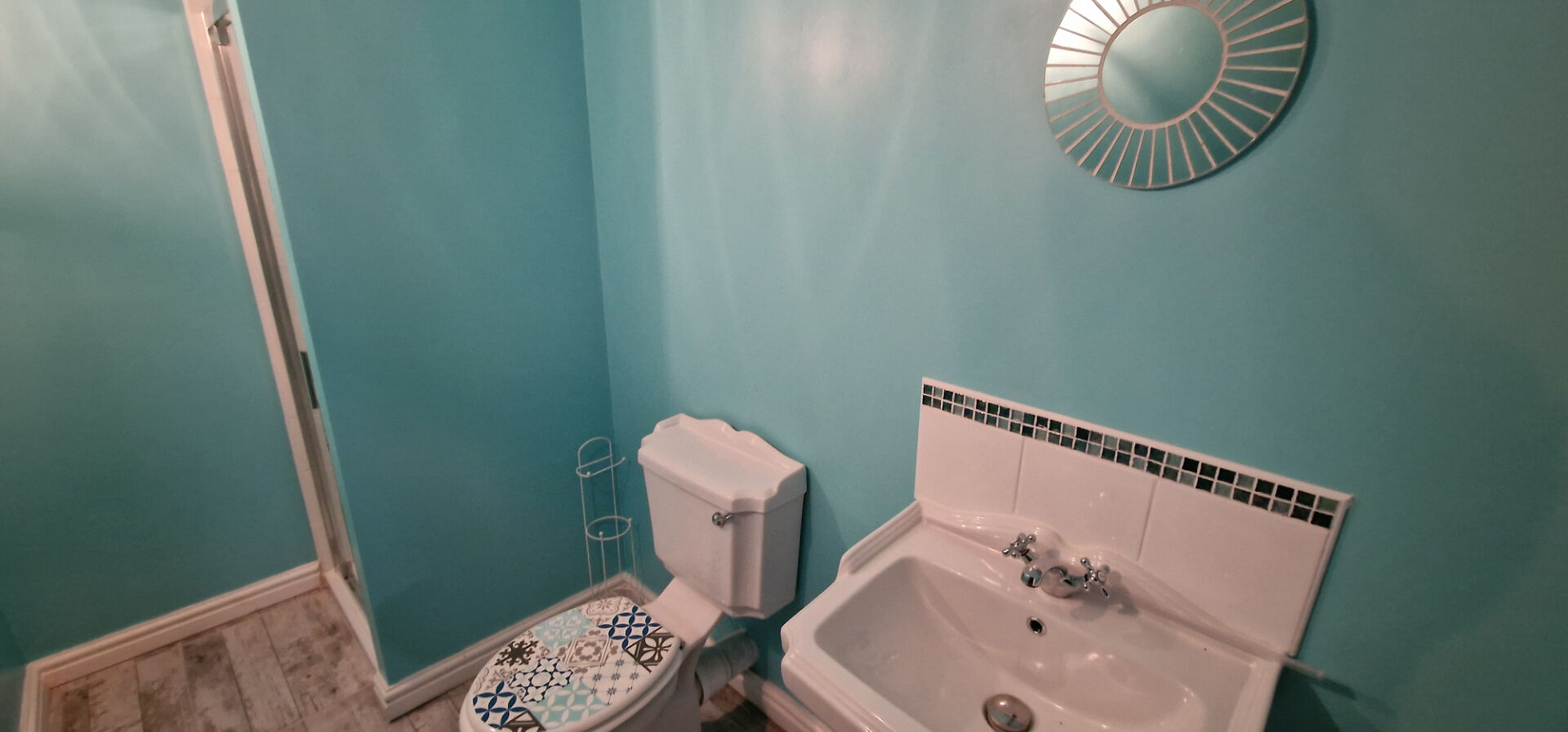 Bright bathroom featuring turquoise walls, a modern sink, and a stylish toilet in Morbihan, Brittany.