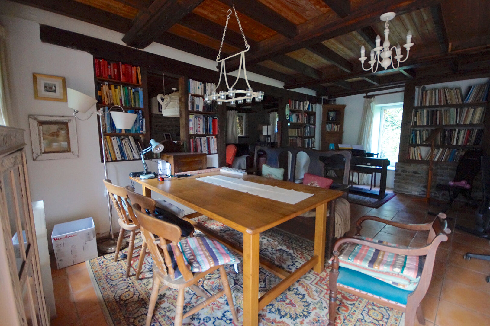 Spacious property in Manche, Normandy, featuring a well-lit study with wooden beams and bookshelves.