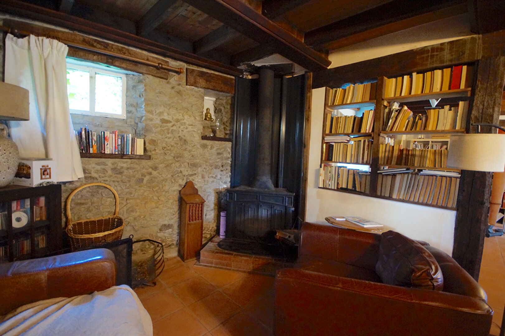Cosy property in Manche, Normandy, featuring a stone wall, wooden beams, and a fireplace in the living area.