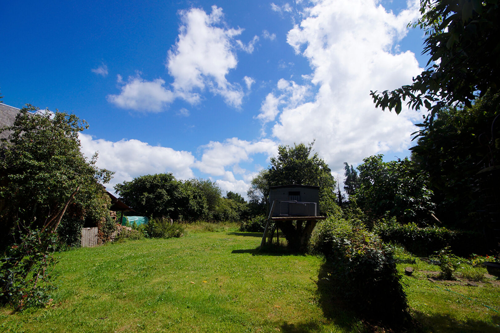 Spacious garden with trees and a playhouse, located in Manche, Normandy, featuring a 4-bedroom property.