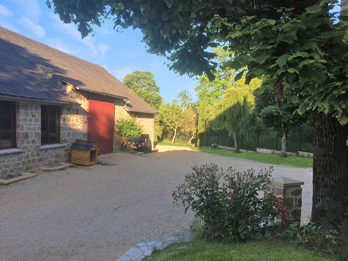 Property in Corrèze, Nouvelle-Aquitaine, features a gravel driveway, stone architecture, and lush greenery.