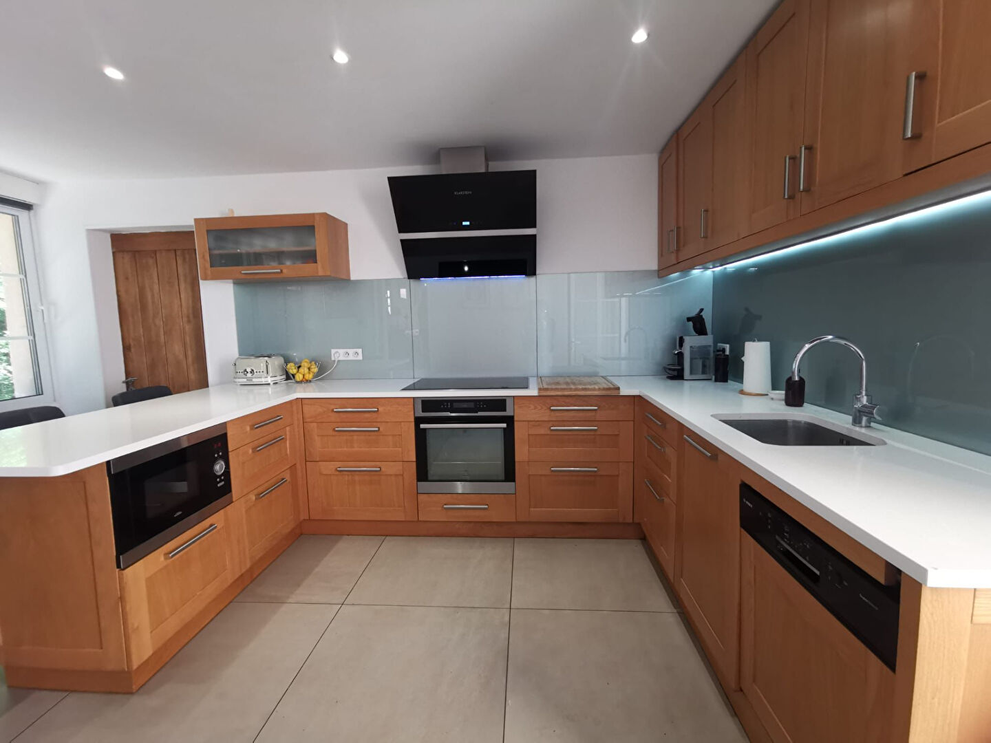 Modern kitchen in property located in Corrèze, Nouvelle-Aquitaine, featuring wooden cabinetry and sleek appliances.