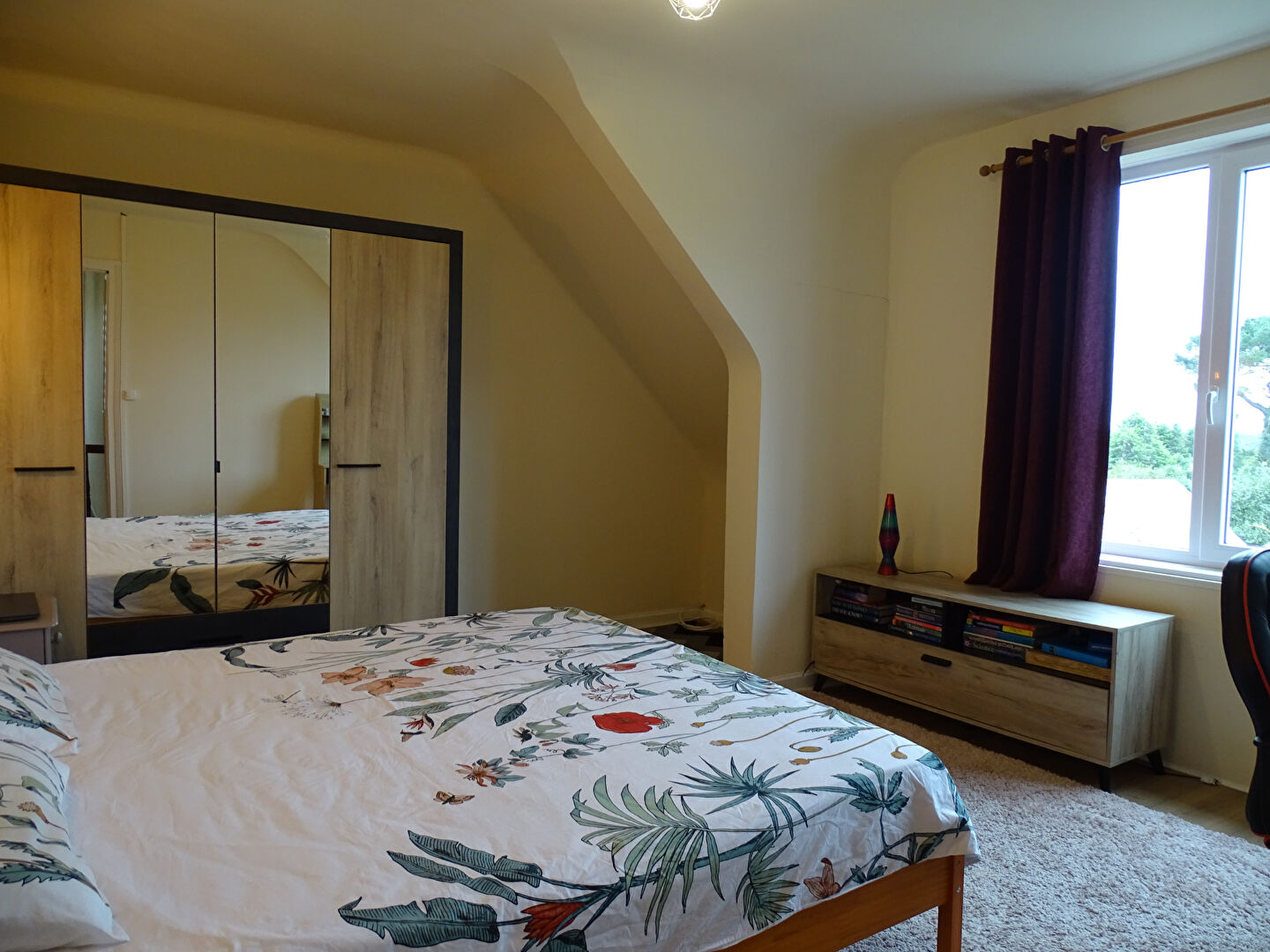 Spacious bedroom with floral bedding, wardrobe, and natural light in Finistère, Brittany, featuring 3 bedrooms.