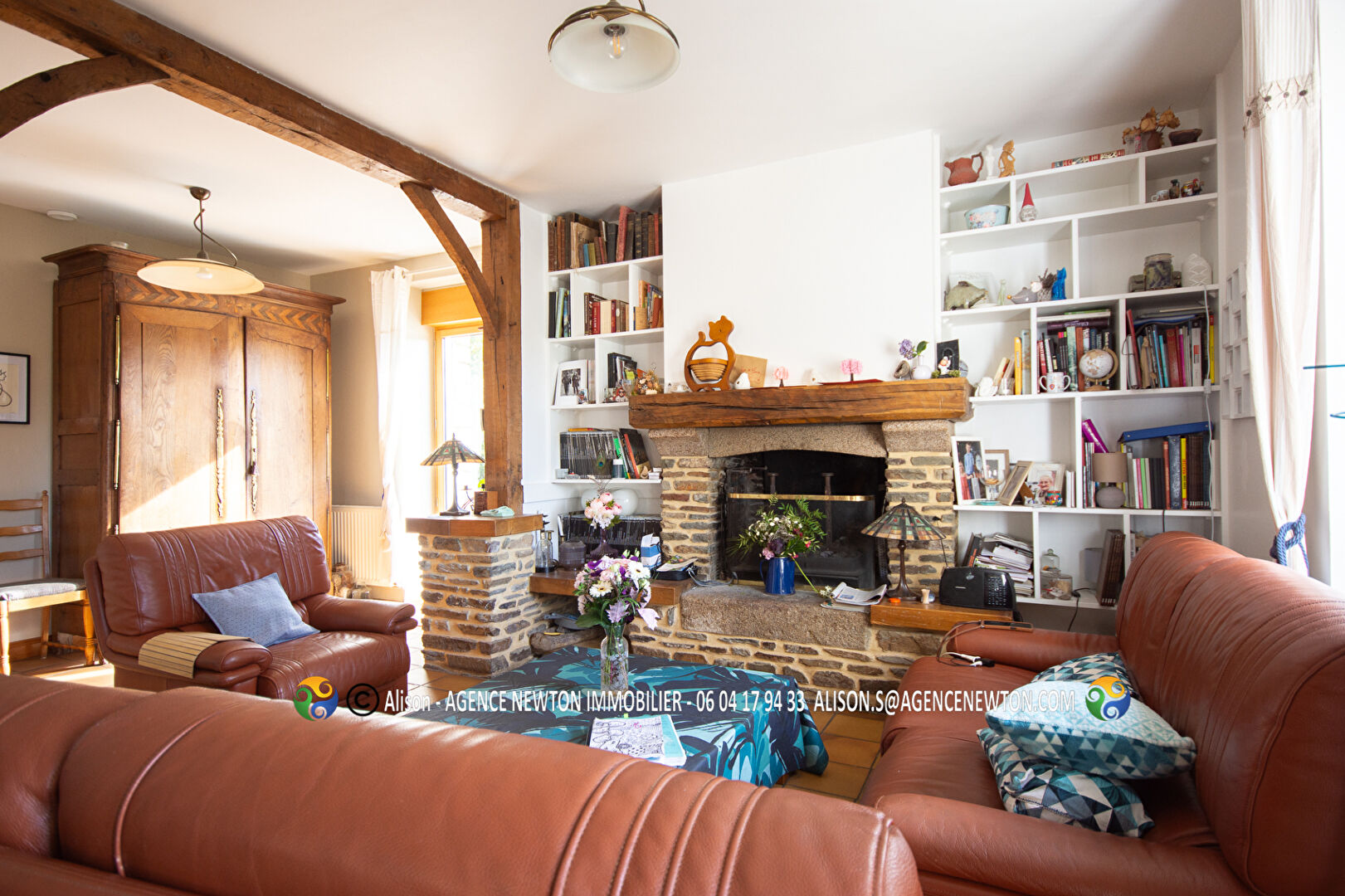 4-bedroom property in Manche, Normandy, featuring a cosy lounge with a fireplace and bookshelves.
