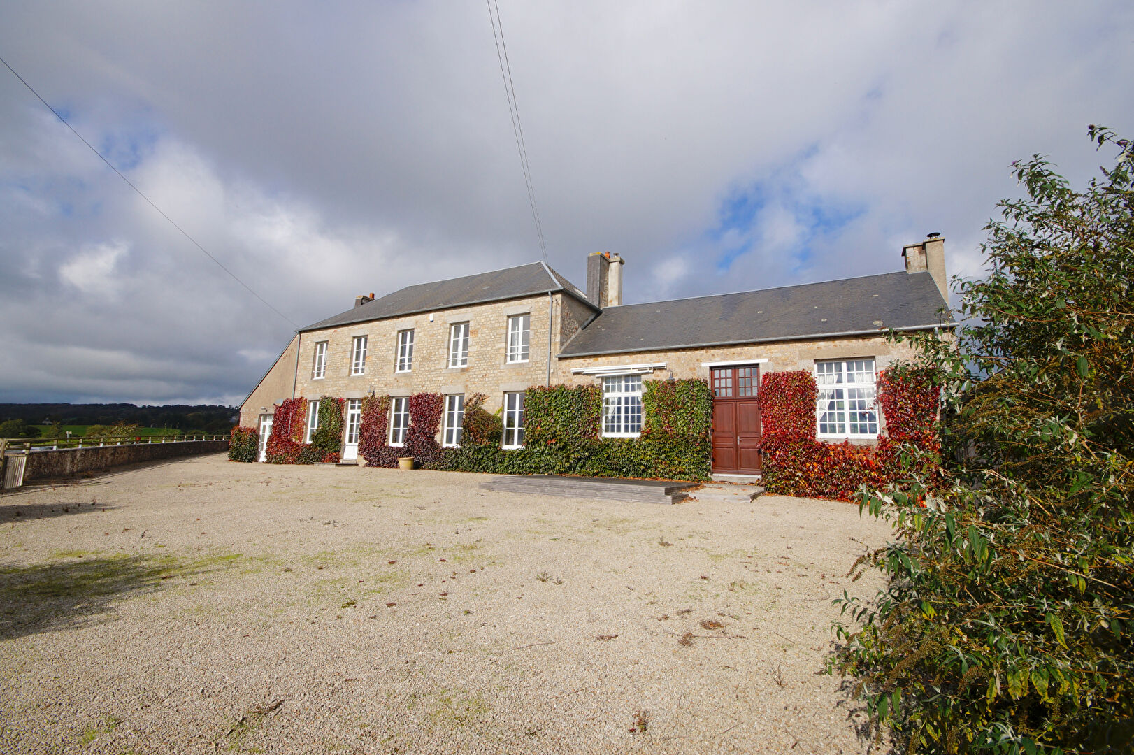 Spacious property in Manche, Normandy, featuring a distinctive stone façade and landscaped surroundings.
