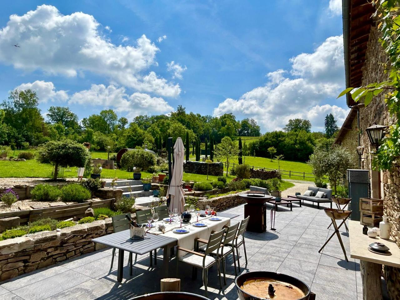 Spacious outdoor terrace with dining area, overlooking lush gardens in Haute-Vienne, Nouvelle-Aquitaine.