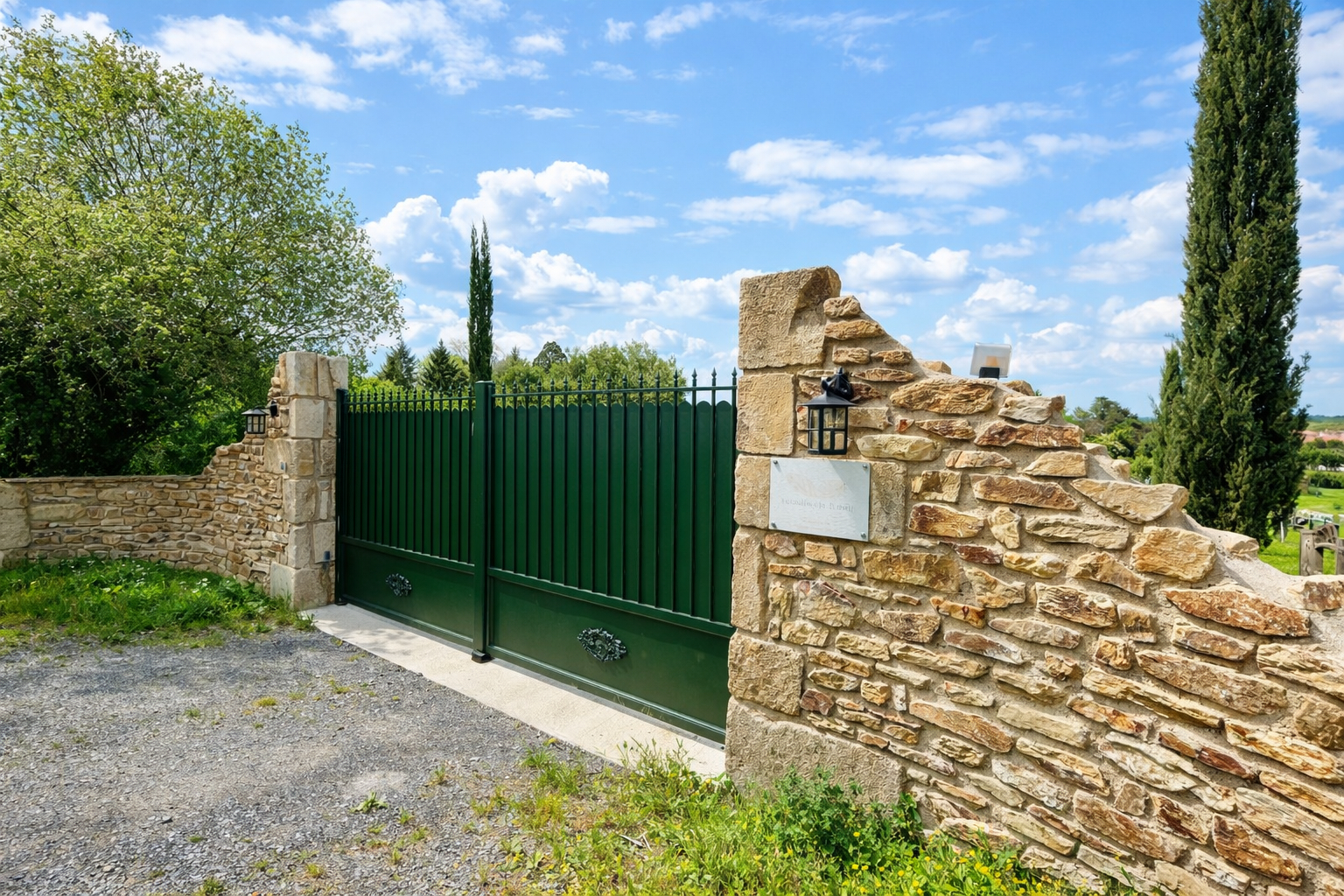 Entrance gate to a property in Haute-Vienne, Nouvelle-Aquitaine, featuring stone walls and landscaped surroundings.