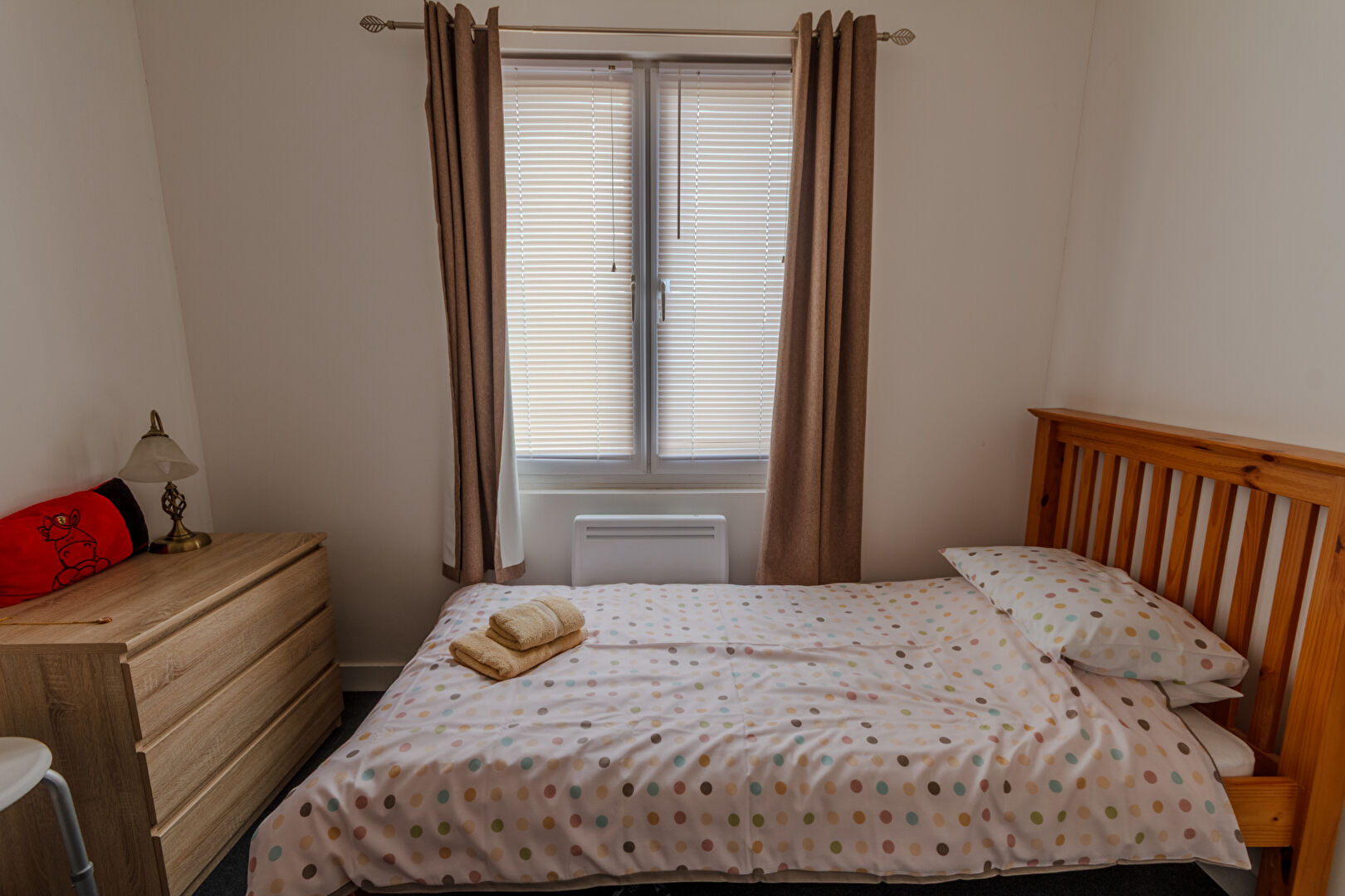 Bright bedroom with single bed, wooden furniture, and window in Manche, Normandy. Suitable property for comfortable living.