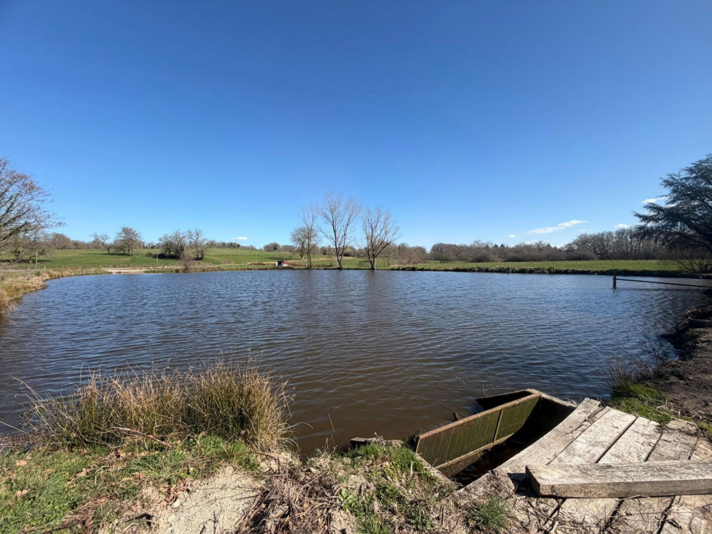 Scenic view of a lake with wooden dock, located in Haute-Vienne, Nouvelle-Aquitaine, showcasing natural surroundings.