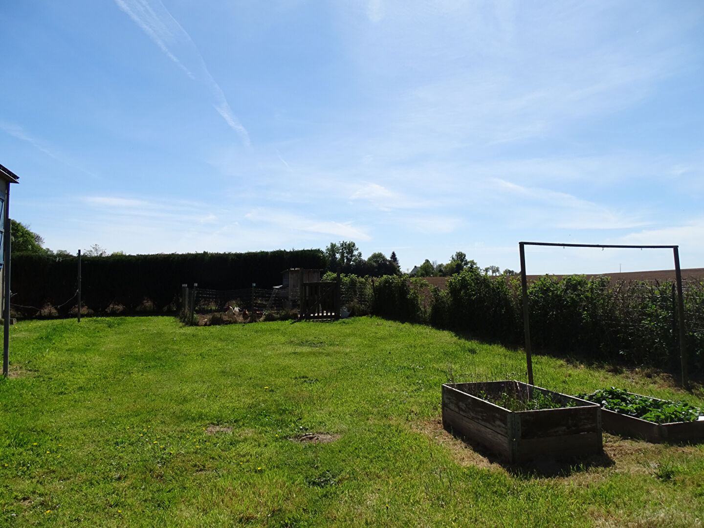 Spacious garden with vegetable beds in Finistère, Brittany, featuring lush green grass and hedgerows.
